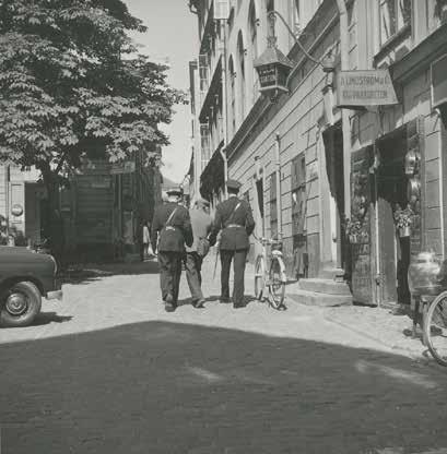 EN MAN ESKORTERAS AV TVÅ POLISER UTANFÖR POLISSTATIONEN. FOTO: T. JERNEMAN 1956. SSM:S ARKIV, F52525.