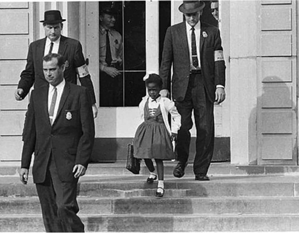 1960 blev sexåriga Ruby Bridges den första att bryta rassegregeringen på William Frantz-skolan i New Orleans. Fotot visar Ruby på skolans trappa, eskorterad av federala poliser.