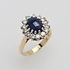 Blå cabochonslipad safir med chatoyance och 14 briljantslipade diamanter om totalt ca 1,4 ct, fattade i 18k vitt guld, stämplad 750,