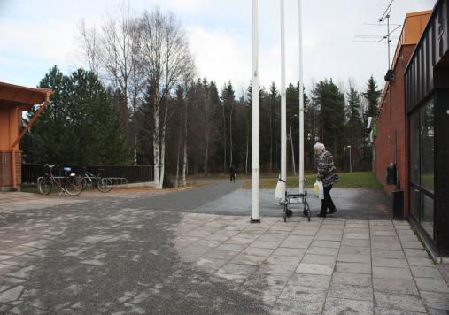 ej PLATS 9 Vid Konsum 1. Mörkt efter ena sidan mot hälsocentralen. Lampor finns på fasaden men de är släckta.. Bilar kör runt och buskör på kvällar 1.