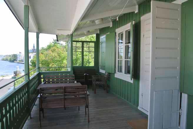 DET ÖSTRA HUSET HAR EN VERANDA MOT VATTNET MED FIGURSÅGAT RÄCKE OCH TAK SOM BÄRS AV KOLONNER. FOTO: J. MALMBERG. en tillbyggnad från samma tid med fasad av grönmålade, liggande panelbrädor.