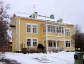 Om- och påbyggd för Konsthögskolan i Umeå 1986. Sedan 2010 granne med och skymd av den nya arkitekthögskolan. Vacker fasad i grått cementtegel med rödaktiga fogar.