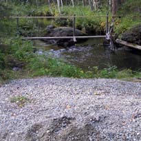 Lekbotten i Tuggenbäcken bakom den stora sten som syns i föregående bild. Mindre stenar i nedkanten av bilden bidrar till förankring och styr strömmen.