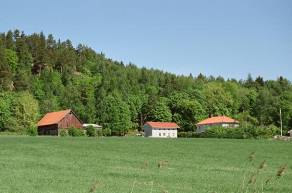 Välbevarad trädgård med gräsrundel och grusgångar. Ladugård samt mindre uthusbyggnader.