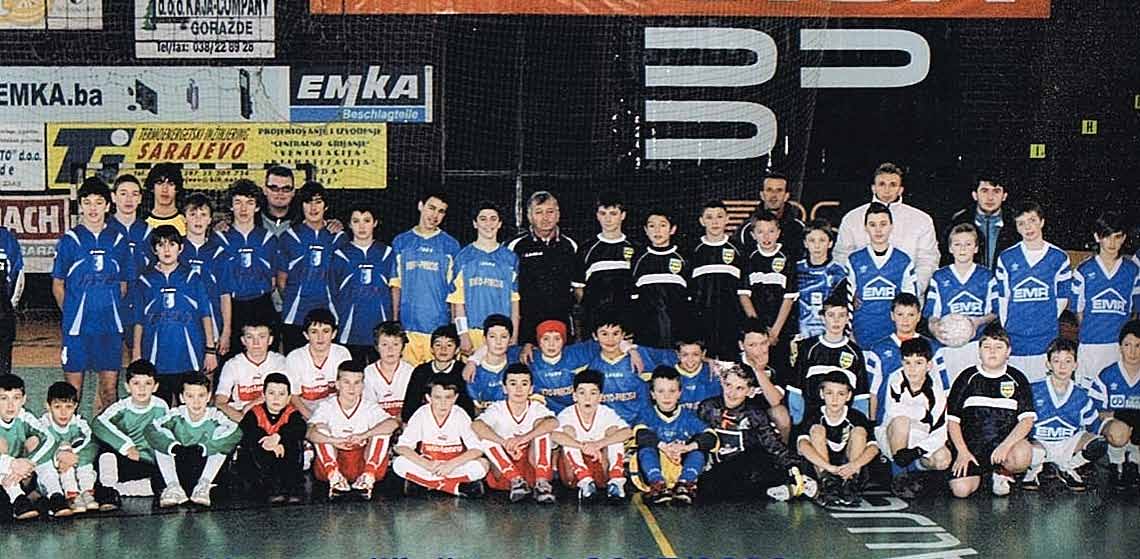 Trener Selver Tozo (u sredini iznad dječaka s crvenom trakom na glavi) sa saradnicima i učesnicima škole fudbala FK Goražde Dok posmatramo brojne dječake i djevojčice na popodnevnom treningu u