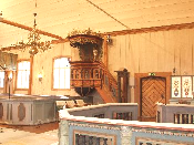 Interiör Kyrkorummet är täckt med ett tunnvalv av vitmålade brädor och väggarna har vitmålad stående ospåntad panel av ojämna brädor lagda mellan utskjutande strävpelare.