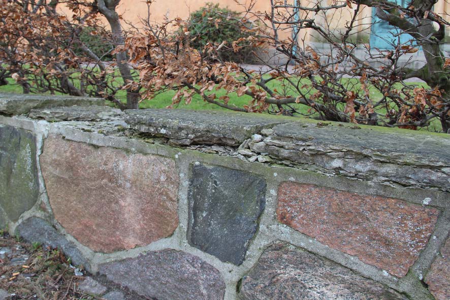 Ovan: Muren mot söder före renovering med lösa stenar i hörnet mot uppfarten till