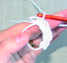 Magisk ring - steg för steg 1. Forma garnet till en ring genom att korsa den långa tråden över den korta. Den korta garnänden ligger i handen. 2. Stick in virknålen i ringen... 3.