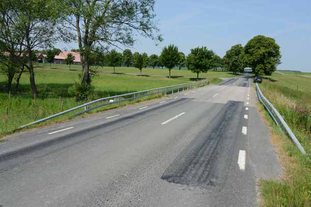 Trafikanter längs väg 1624 ser endast de nyligen uppsatta rörräckena och fokus ligger snarare på allésystemen fram till gården än på bron.