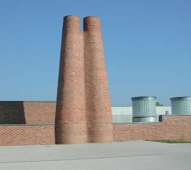 Teknikbyggnad som binds samman av den tydliga mönstringen i fasadmaterialet. De sammankopplade tornen får genom form och material en sträng, mycket sammanhållen karaktär.