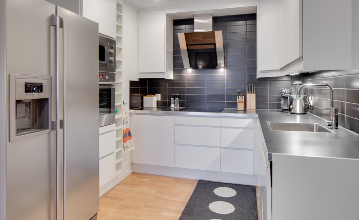 Kök Köksinredning från IKEA med vita släta köksluckor och grått kakel över diskbänken.