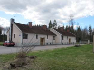 En del av lönnallén i Åfors, med hyttan och vedförrådet till vänster i bild och fd brukshandeln till höger.