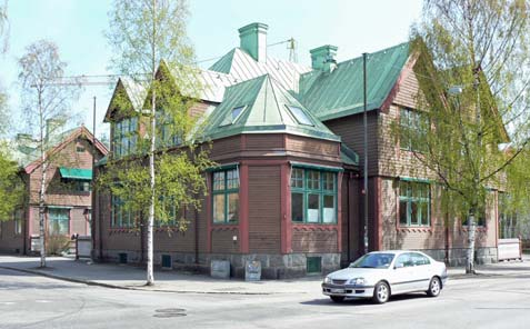 6 (12) En stram volym i gråvit puts med symmetrisk fasad mot Storgatan. Fasader med klassicistiska detaljer med låga reliefer i gråvit puts.