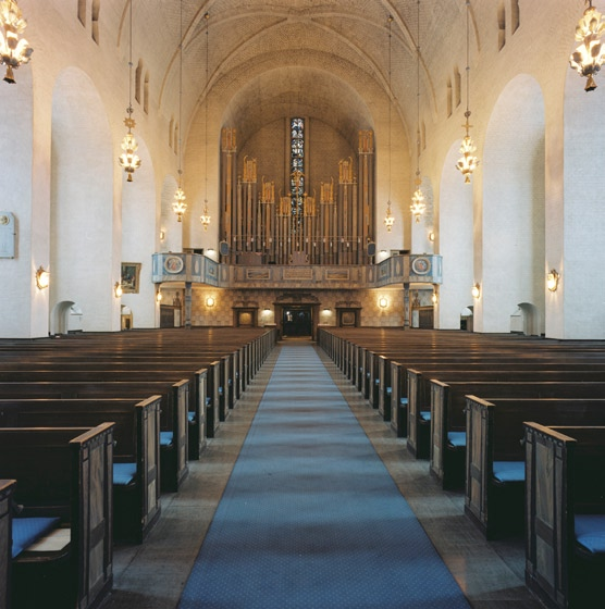 Det finns även plats för ett flyttbart altare och dito dopfunt m m. Orgelläktaren i väster med utsvängda partier i norr och söder vilar på stöd i form av två dekorativt skurna pelare.