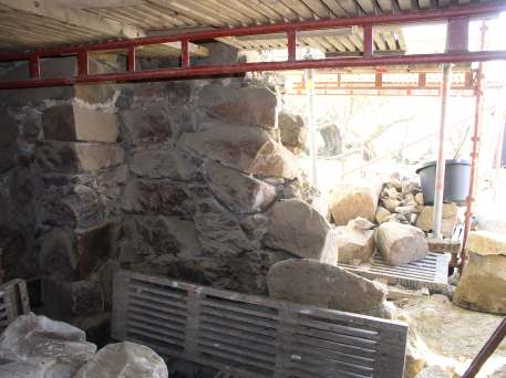 Murverket från insidan under rivning Skalmurad vägg med grova stenar i ytterliv och mindre stenar lagda i lerbruk i murens kärna.