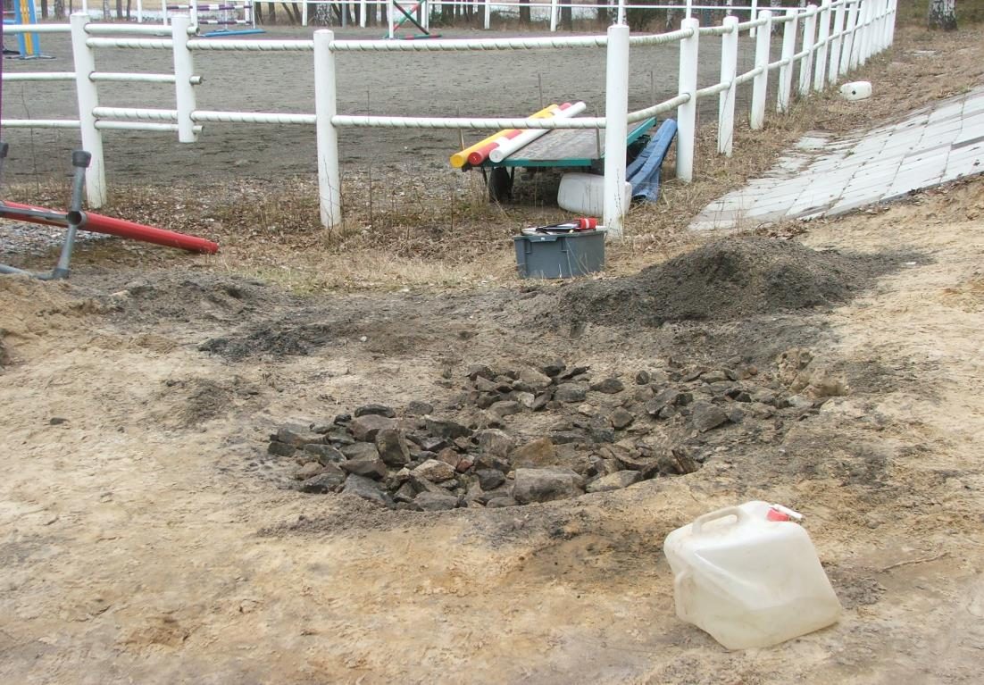 Figur 10. Den undersökta härdgropen med paddocken i bakgrunden, foto från sydöst. Foto: Björn Wallbom.