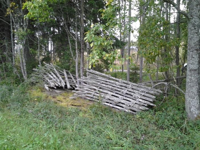 Lada med en blandning av runda och fyrkantshuggna stockar. Ladan är i bra skick och har plåttak.