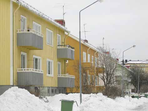 av ljusa tvåvånings hyreshus i trä med garage i souterrängvåningen mot gatan.