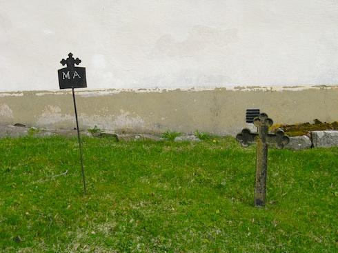Strax utanför kyrkogårdsmuren står en brunmålad klockstapel som uppfördes på 1920- eller 1930-talet.
