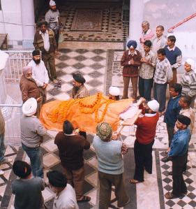 Slutet av en text Den döda har fått en hedersskrud av gurun i templet och bärs ned till kremeringsplatsen i Varanasi.