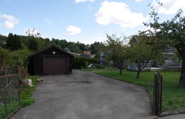 Trädgården sett från korsningen Lyckogatan/Gråvidegatan Den asfalterade tillfarten som leder fram till garagebyggnaden.