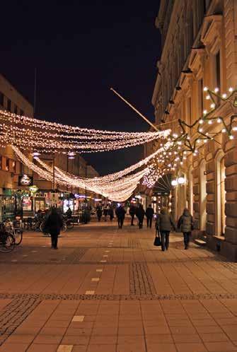 Uppsala Universitetsbibilotek. Julgranar med belysning skapar julstämning. Granarnas blåvita ljus kontrasterar vackert mot den varmt upplysta fasaden.