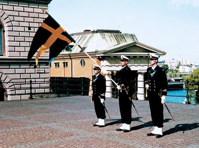 Fanföring från struken fana Fana förs från struken till blottad genom att högra handen för fanstången nedåt och förbi högra sidan så den väl passerar