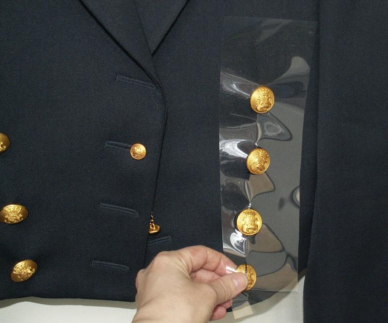 En våt uniformsjacka med metallknappar kan skyddas mot korrosion genom att man klipper till en bit plast (i det här fallet polyester, så kallad Melinex) och trär över knapparna för att isolera dem