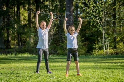 är riktad framåt. Håll i en skidstav/pinne med brett grepp och sträck armarna rakt över huvudet. Blicken ska under hela övningen vara riktad framåt.