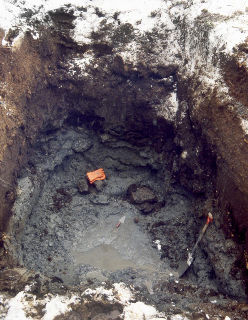 Figur 25. En av de maskin grävda groparna vid Mossatjärnen. I botten på gropen finns en isräfflad hällyta. Räfflor i murslevens riktning, nordväst sydost. Foto: Robert Lagerbäck.