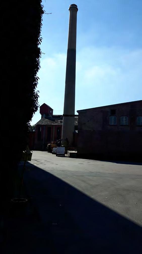 Till vänster skorstenen så som den möter besökare som kommer in på bruksområdet. Till höger lastbryggan till Gamla lumpen, den byggnad som ligger alldeles intill skorstenen.