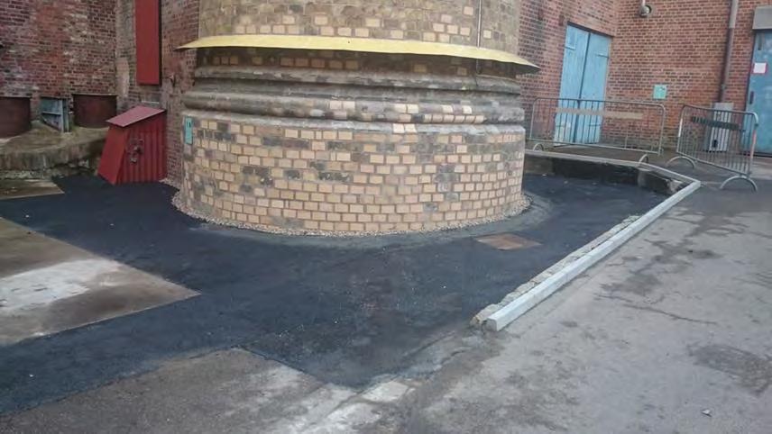 Bilden togs i samband med att såväl mur- som avvattningsarbetet var färdigställt. Här kan konstateras att åtgärderna, framförallt den nya asfaltsbeläggningen, främjat tillgängligheten till skorstenen.