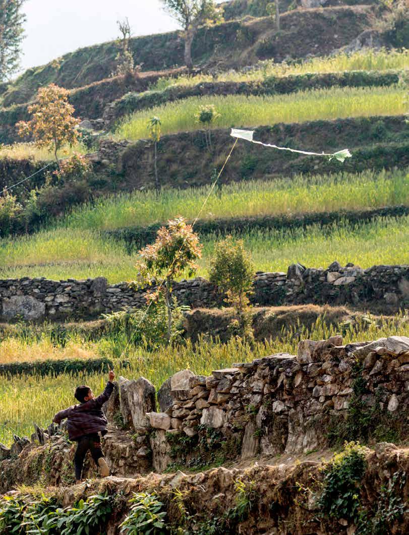 Pojke i Nepal flyger drake på en odlingsterrass som anlagts för att hålla jord och näring kvar i marken.
