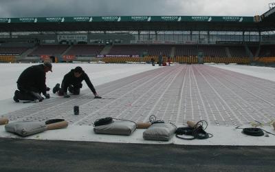 Elektrisk uppvärmning installerades mellan stötkuddarna och konstgräset Installation utfördes i princip på samma sätt som en standardinstallation för en DEVI-matta Särskilda kolspikar användes i