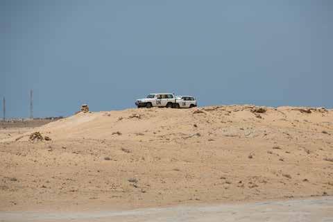 Termometern har krupit över trettiogradersstrecket. Vinden sveper över Sahara och river upp ett finkornigt damm. Salha Moulay sänker sakta kikaren och pekar norrut. Ser du kullen där borta?