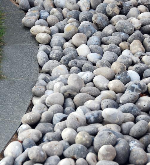 VATTEN Gården med Vatten som tema består av en stiliserad strand, natursten i olika storlekar