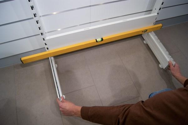 Om man har en vägg som är i det närmaste lodrät att justera emot, kan man hålla stolpsetet mot väggen och justera upp höjden på ställskruven () som INTE når ned till golvet.