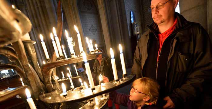 en pappa med sin dotter tänder ljus under gudstjänsten i uppsala domkyrka. foto: magnus aronson/ikon uttryck för att Svenska kyrkan i sin mångfald och geografiska spridning ändå är en.