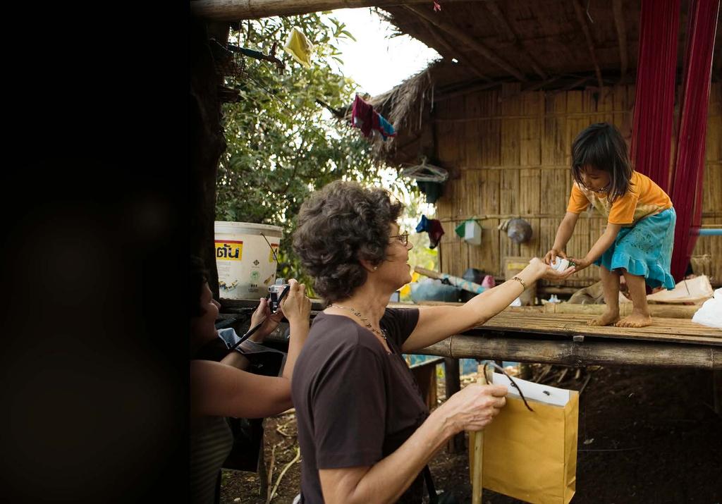 Några turister köper souvenirer från ett barn vid en strand i Thailand.