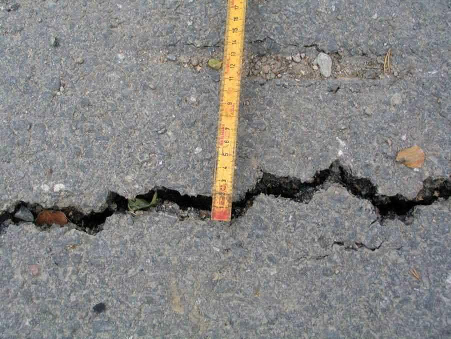 Figur 43. Exempel på spricka i asfalt som behöver åtgärdas. Vägen har försetts med en kantsten för att förhindra att vatten från vägen rinner ner i slänten och skapar erosion.