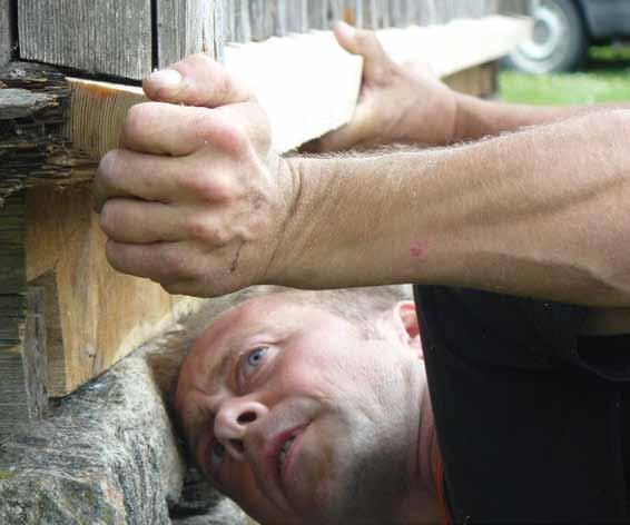 En deltagare på en byggnadsvårdskurs i Halland, Floa Backe hembygdsgård, sätter en ny dropplist på plats.