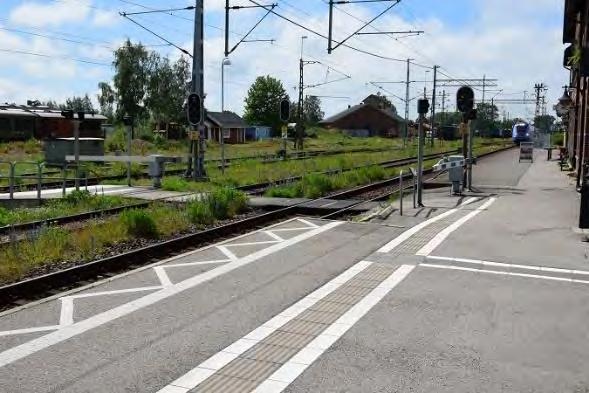 Förbindelser En planövergång av undermålig kvalitet förbinder plattformarna i västra änden av stationen. Ytskikt i såväl betong som asfalt och trä.