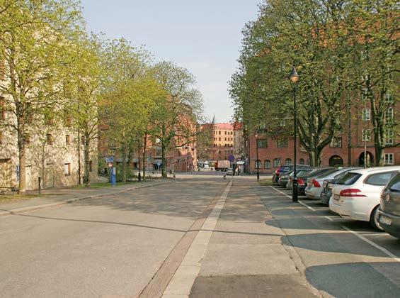 Olof Wijksgatan norrut, Artistens tegelfasad skymtar bakom kastanjeträd, markparkering mot gamla Hovrätten.