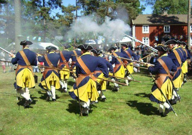 Karolinerna marscherar och skjuter salut på nationaldagen 2016 i Horda Hembygdspark i Rydaholm. Ryktet förtäljer att härföraren hämtats från SSA!