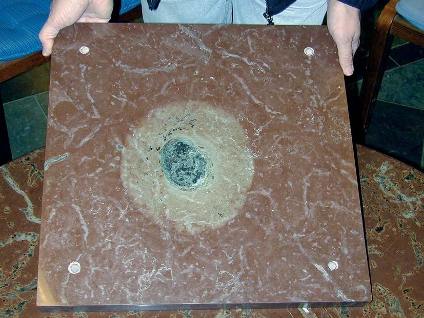 Bild 12. En av de mycket vetenskapligt intressanta fossila stenmeteoriter som hittats i Thorsbergsbrottet (Kinnekulle). Kring meteoriten har järnoxiden i den röda kalken reducerats i den grå zonen.