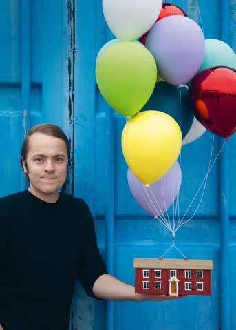 Erik Olof Wiklund visar upp konstverket»luftslott«, där hälsingegården Löka i Alfta svävar under ballongerna.»fhlyttmåhl«.