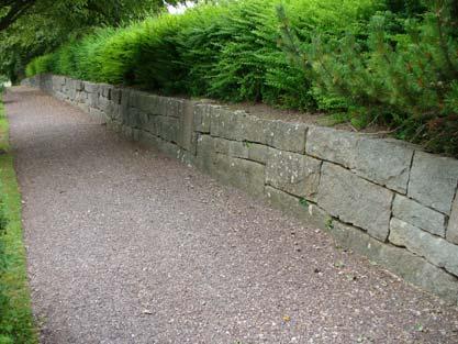 Söder om trappan övergår muren från stödmur till en fristående kallmurad mur. Stenarna i muren varierar i storlek och beskaffenhet.