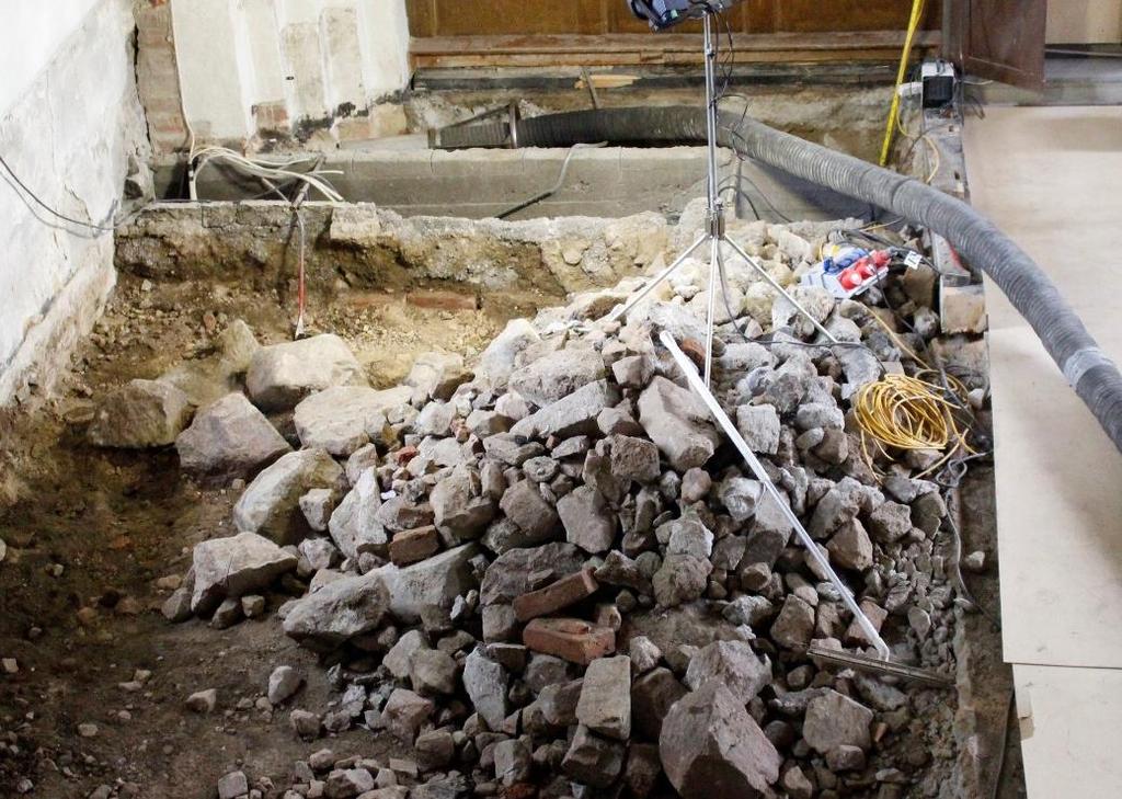 Lager 1 Direkt under betonggolvet fanns ett 0,2 0,4 m tjockt lager av 0,2 0,3 m stora stenar, enstaka tegel, grus och sand (figur 16). Lagret täckte hela långhusets yta.