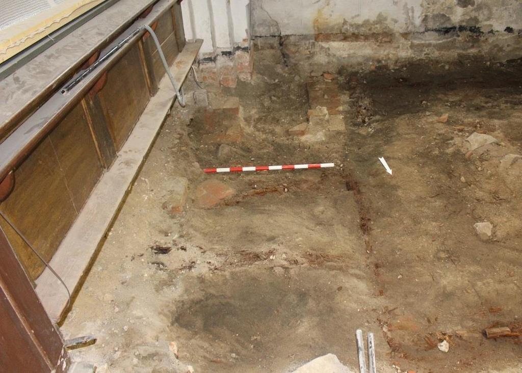 Korskranksfundament 5 I långhusets sydöstra del, alldeles intill koret, påträffades en 2,5 m lång och 0,3 m bred tegelmur 0,5 m under den sentida golvnivån (figur 21 23).