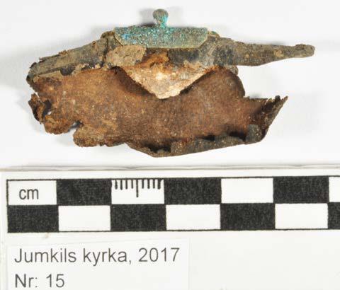 Skinnet är fragmentariskt och styvt och på dess insida sitter tester av dess pärm av trä, klämt mellan skinnet. Beslaget före konservering.